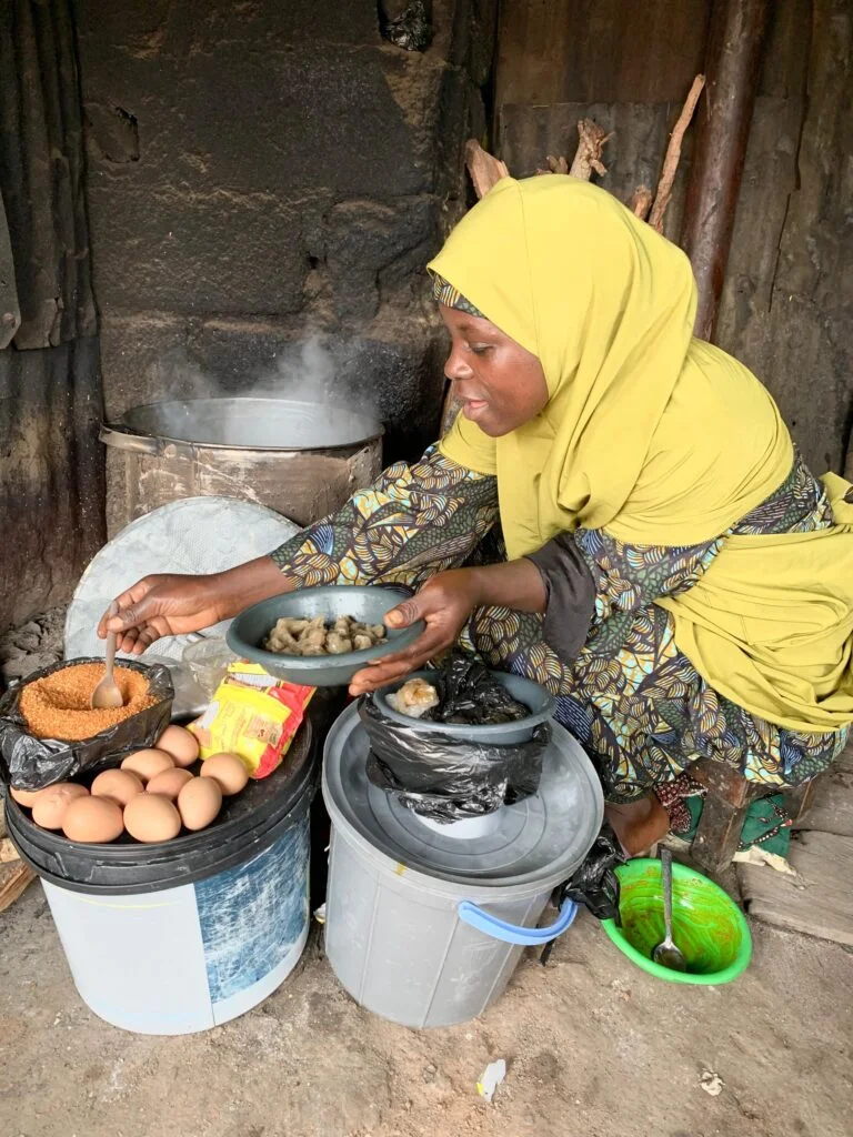 Maryam Ibrahim preparing and serving Dan Wake at her roadside food stand in Rigasa, Kaduna.
