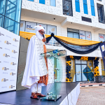 The Alternative Bank Gwarinpa branch opening ceremony in Abuja, with a traditional ruler speaking at a podium outside the bank.