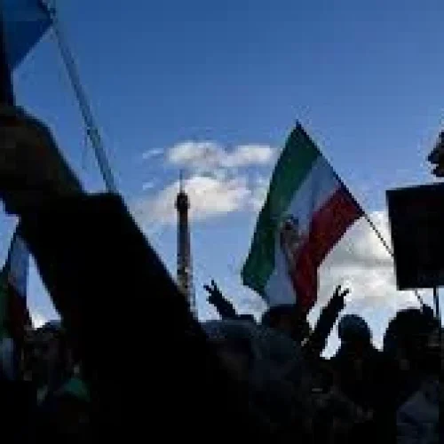 Protesters in Tehran holding banners and raising their fists amid heavy police presence during nationwide demonstrations in Iran, January 2026.